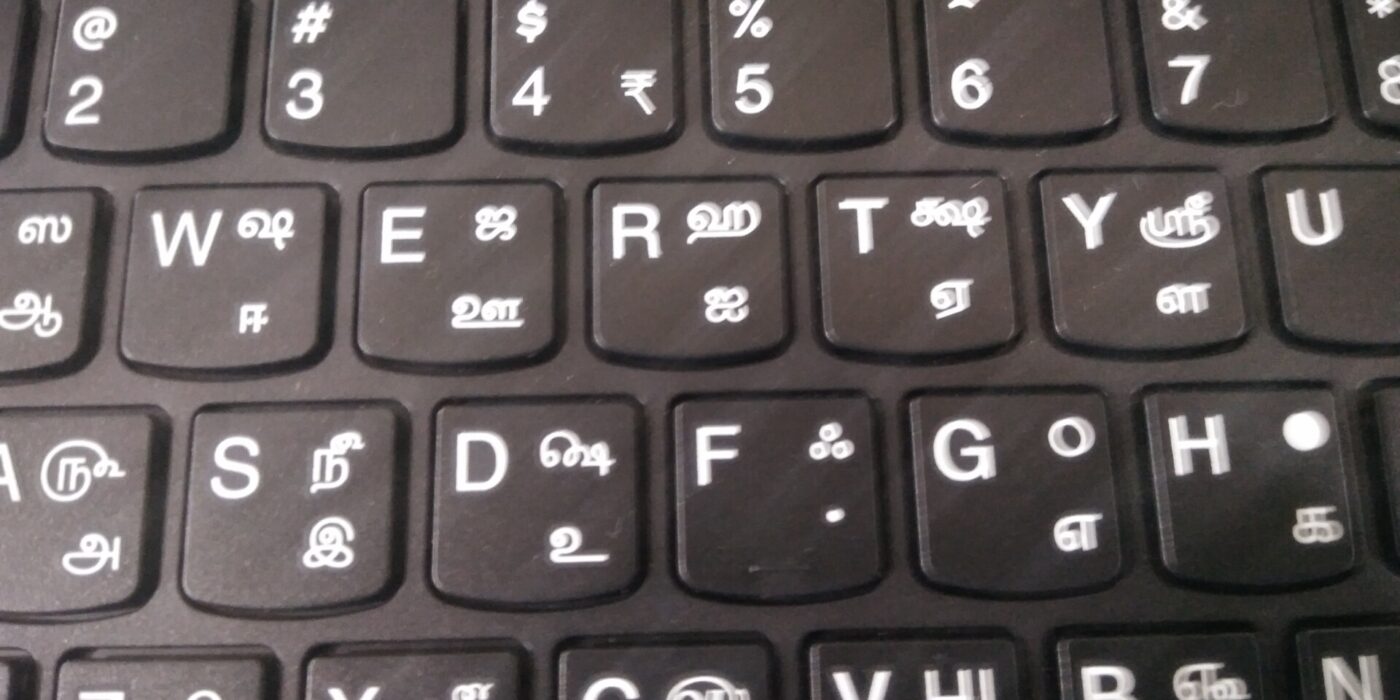 Laptop keyboard with Tamil letters printed beside the English keys, a reminder of real input when designing UI for Tamil text